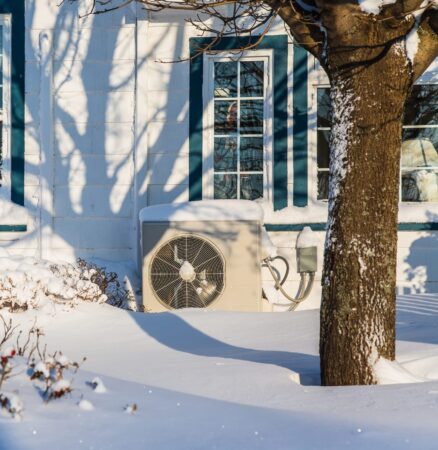 Heat pump unit on the side of a home in winter.